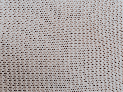A close-up view of a textured woven pattern, likely made from natural fibers such as wool or cotton. The interlocking loops create a uniform and intricate design.