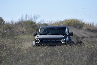 a jeep driving through a field of dirt