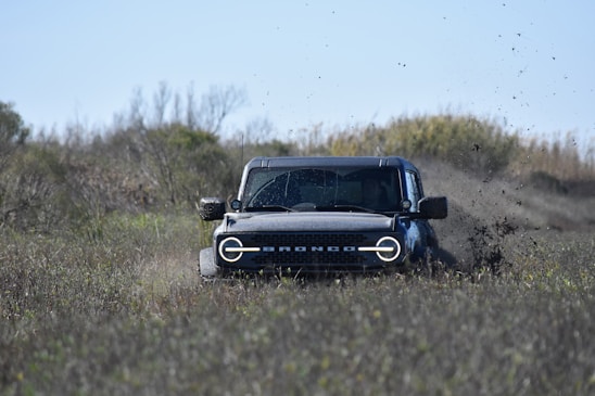 a jeep driving through a field of dirt