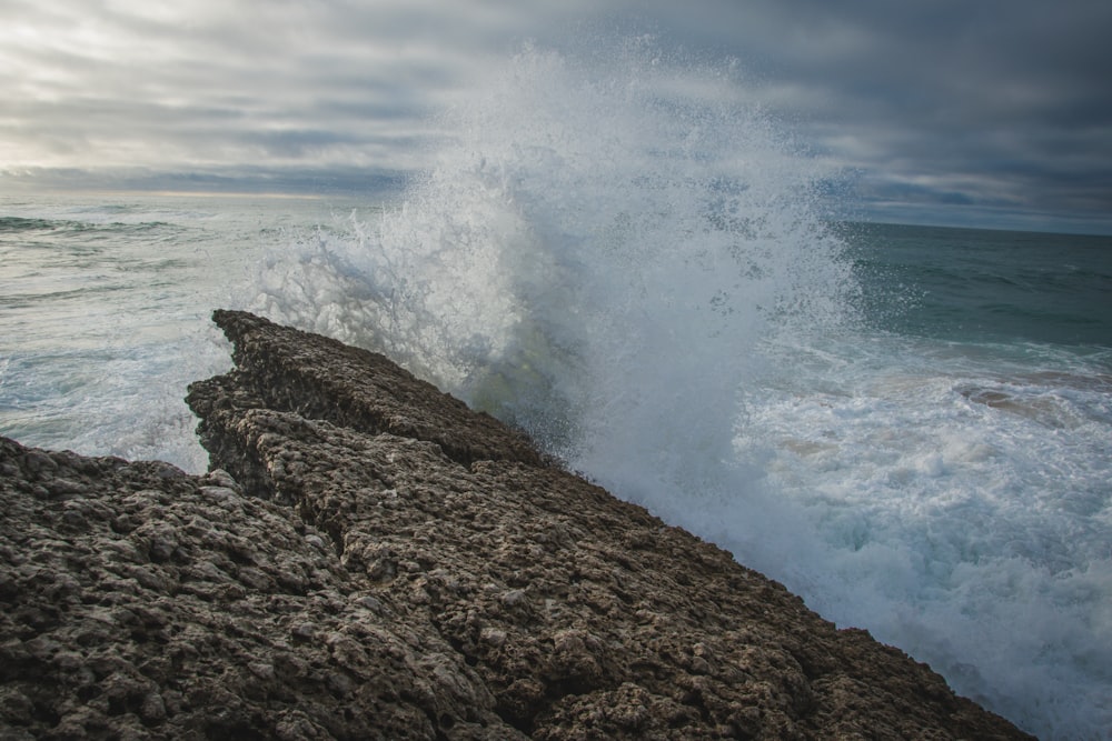 a large wave crashing on a rocky shore