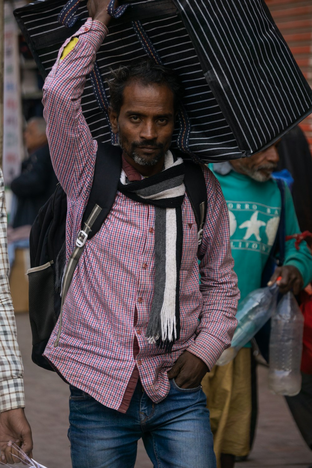 a man carrying a large piece of luggage on his head