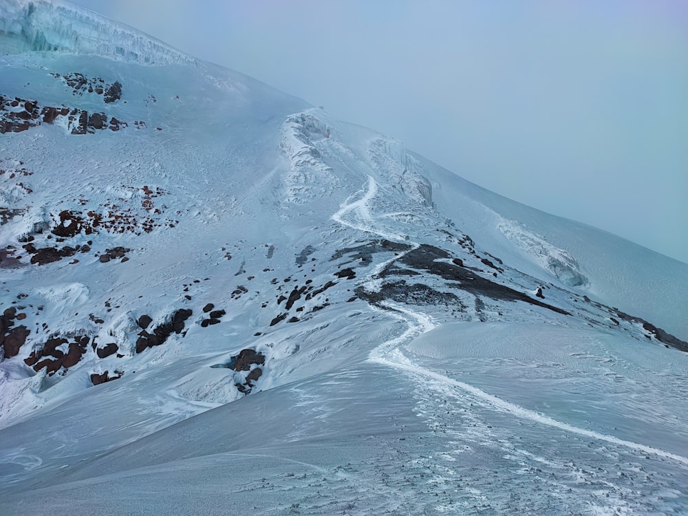 a snow covered mountain with a trail going through it