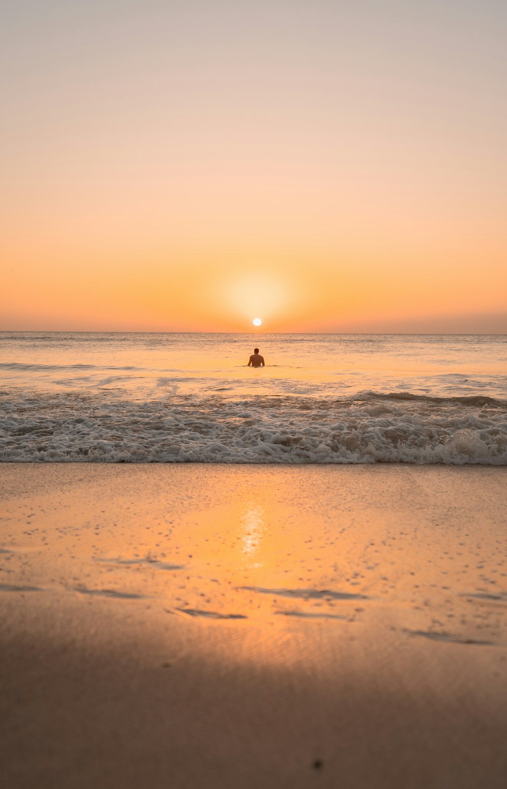 a person riding a horse on the beach at sunset