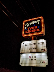 A classic cinema marquee sign illuminated against the night sky. The upper section features the text 'Gateway Twin Cinema' bordered with chasing lights, while the lower section lists movie titles such as 'Antman' and '80 for Brady', both rated PG13.