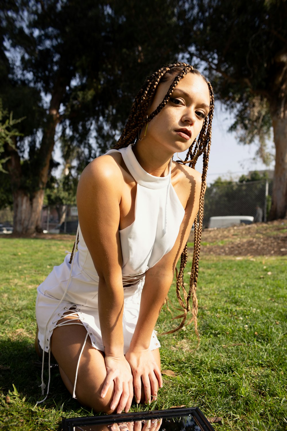 a woman sitting in the grass with her hands on her knees