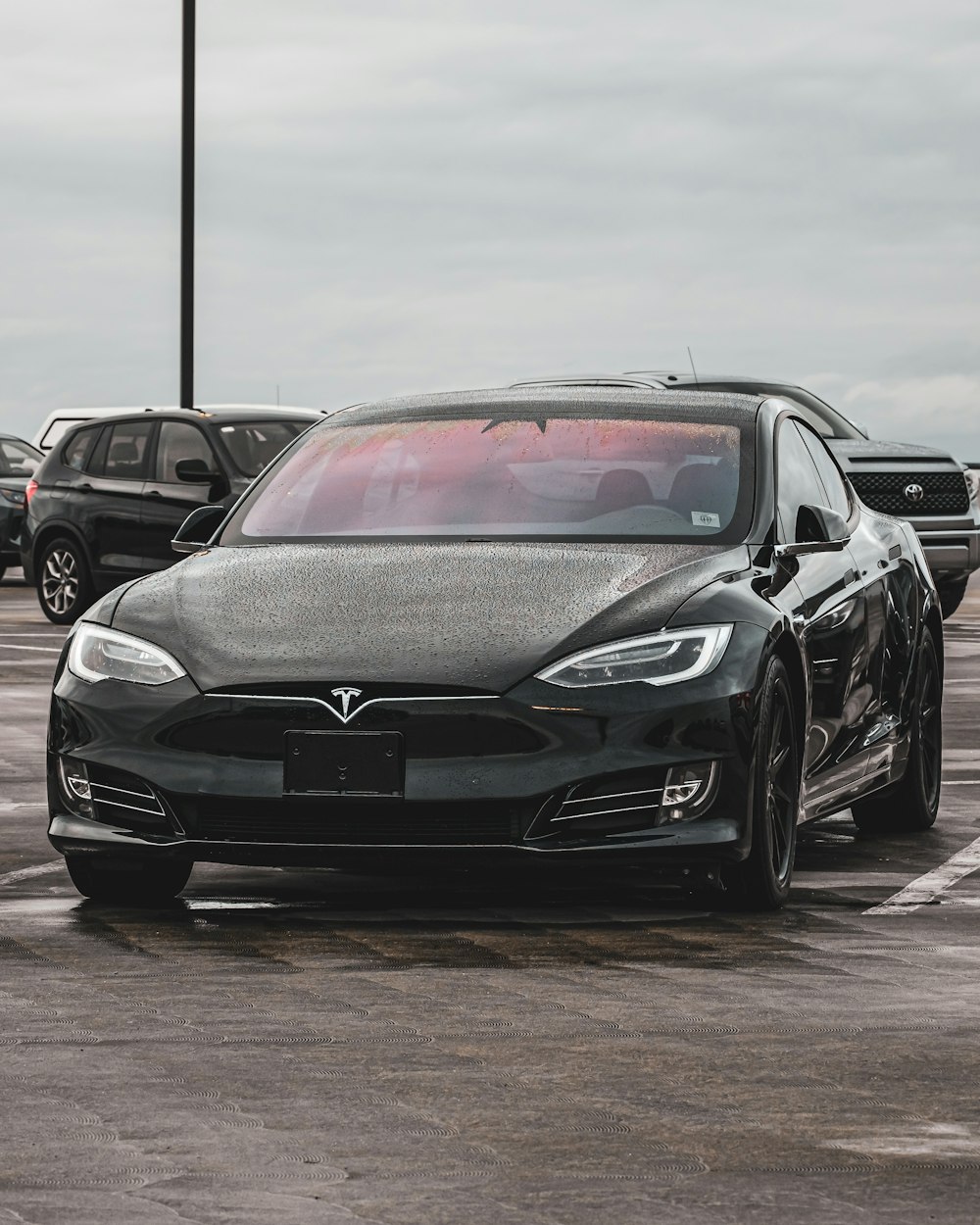 a black tesla parked in a parking lot