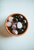 An overhead shot of polished energy stones and a minimalist white puja bowl on an earthy-toned surface