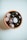 A terracotta bowl containing a collection of polished stones, including quartz and dark stones with a shiny surface, rests on a light background.