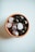 A terracotta bowl containing a collection of polished stones, including quartz and dark stones with a shiny surface, rests on a light background.