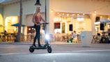 A sleek electric scooter speeding along a city street at sunset.