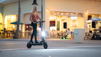 A happy customer riding an evox scooter through a city street at dusk, purple gradient sky overhead.