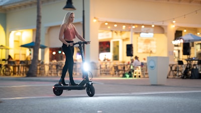 A sleek electric scooter speeding along a city street at sunset.