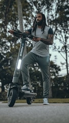 Photo of a rider wearing a 'Scootin My Way' branded hoodie, smiling while holding a scooter