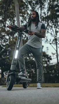 Photo of a rider wearing a 'Scootin My Way' branded hoodie, smiling while holding a scooter