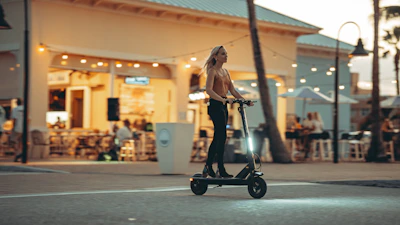 Group of friends riding electric scooters through a modern city plaza.