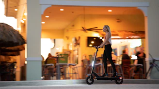 A rider cruising past the bustling Jemaa el-Fnaa square at sunset on an electric scooter.