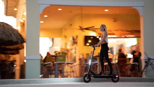 A rider cruising past the bustling Jemaa el-Fnaa square at sunset on an electric scooter.