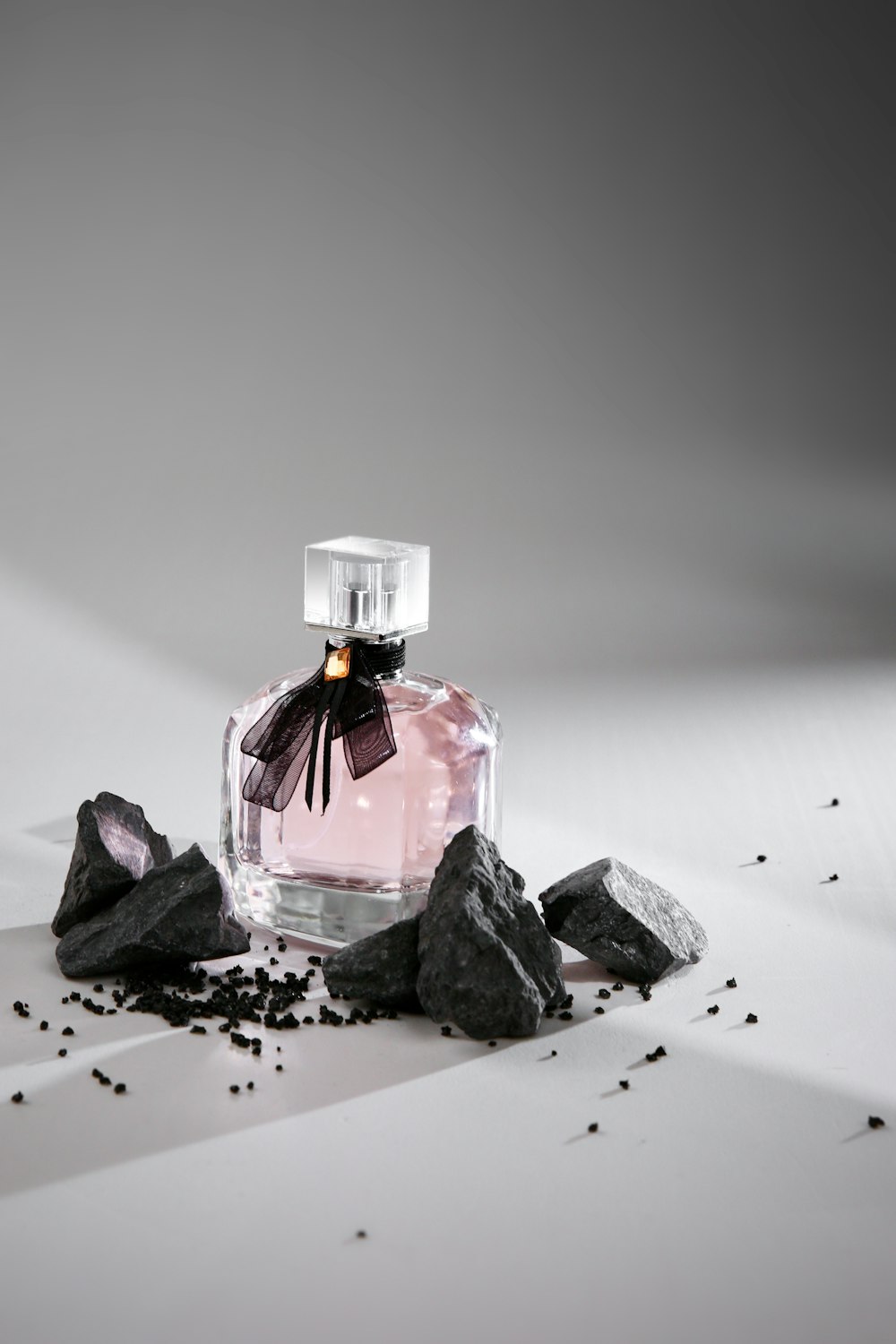 a bottle of perfume sitting on top of a pile of rocks