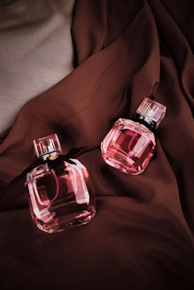 two bottles of perfume sitting on a bed
