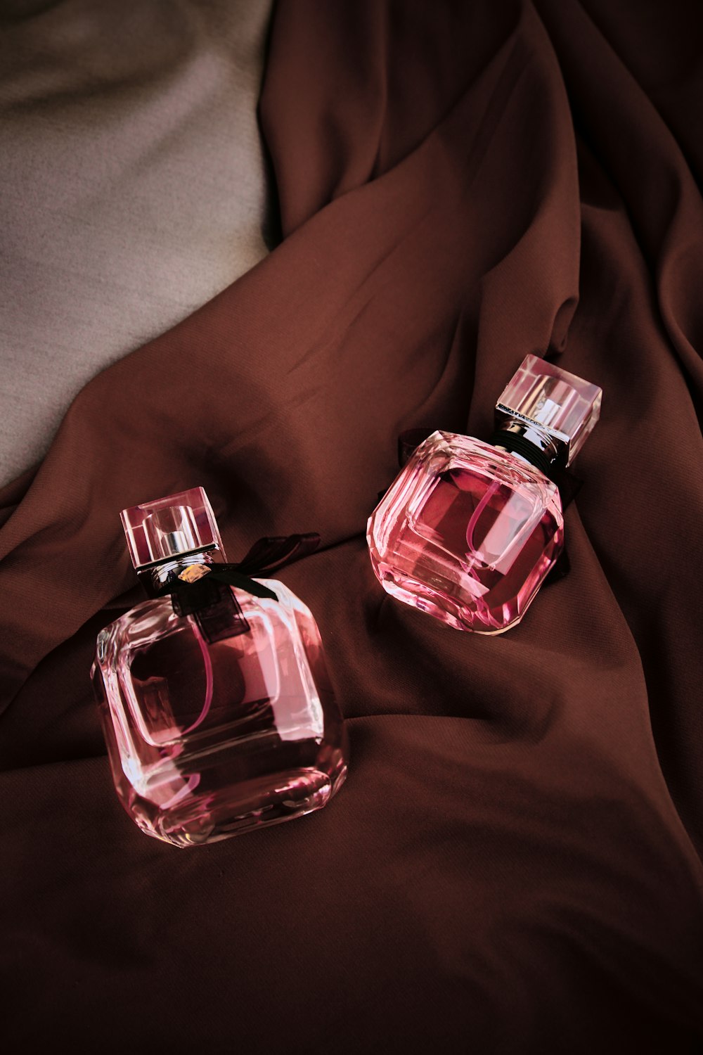 two bottles of perfume sitting on a bed