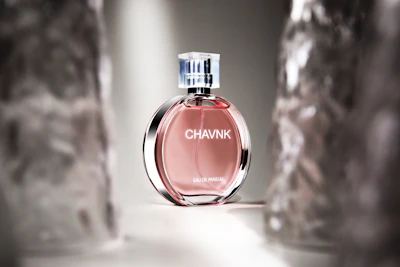 A sleek bottle of amber-hued perfume resting on a marble surface with soft lighting.