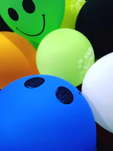 A friendly event animator smiling while holding colorful balloons at a lively party
