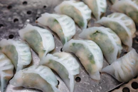 Elegant plate of dim sum dumplings with translucent skins, garnished with fresh herbs.