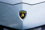 Close-up of a glossy gold crown emblem merged with a supercar silhouette.