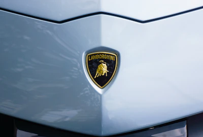 Close-up of a glossy gold crown emblem merged with a supercar silhouette.