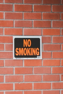 a no smoking sign on a brick wall