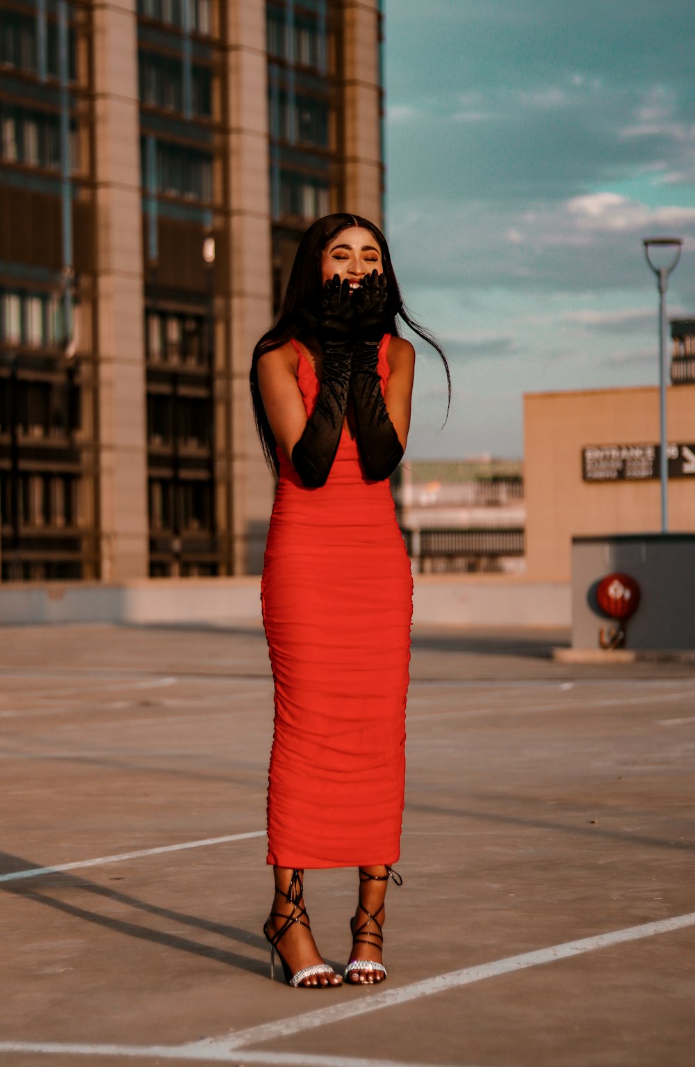 a woman in a red dress standing in a parking lot