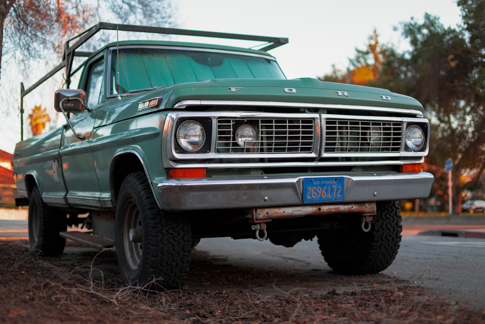 a green pick up truck parked on the side of the road