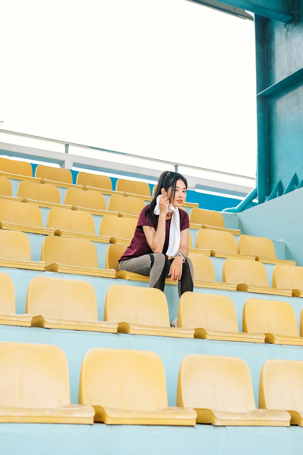 a woman sitting on the bleachers talking on a cell phone