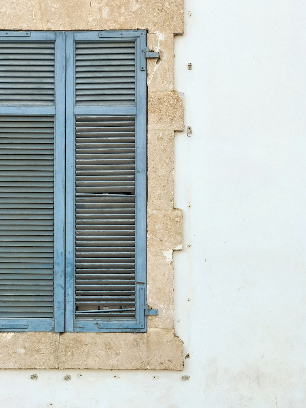 a window with blue shutters on a white wall
