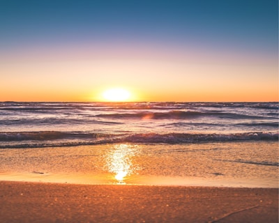A serene beach sunset captured in warm golden hues framed on the lounge wall.