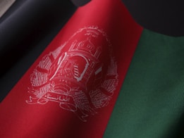 A fabric with vertical bands of black, red, and green, showcasing an intricate emblem in the red band.