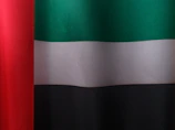 Minimalist shot of raw textured black fabric with hints of red alert and green military hues.