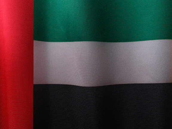 Minimalist shot of raw textured black fabric with hints of red alert and green military hues.