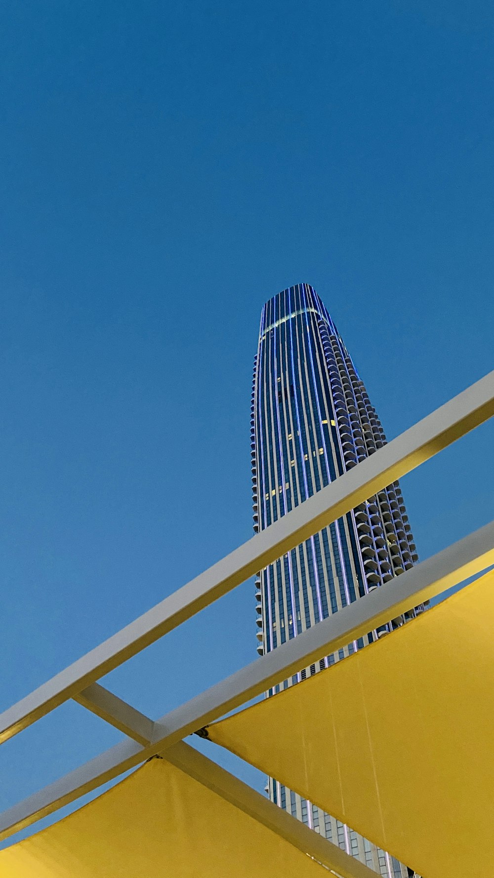 a tall building towering over a city under a blue sky