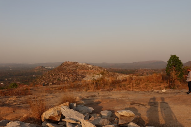 Close-up of a high-tech scanner device in use on rocky terrain with lush mountains in the background.