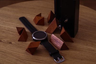 Close-up of sleek, modern fitness trackers and smartwatches on a wooden table.