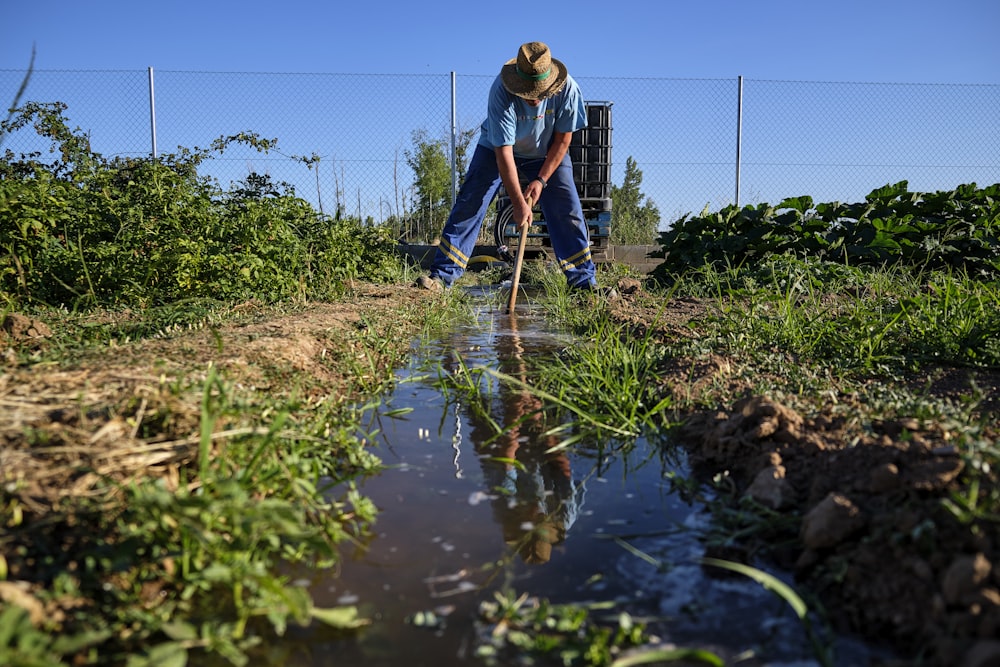 a man in a hat is using a shovel to clean the water