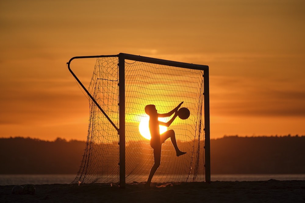 a silhouette of a person playing with a soccer ball