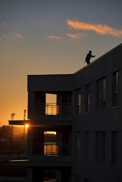 a person on a roof with the sun setting in the background