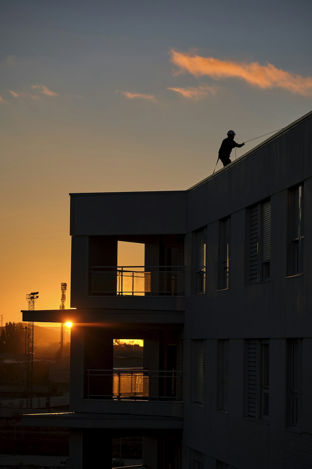 a person on a roof with the sun setting in the background