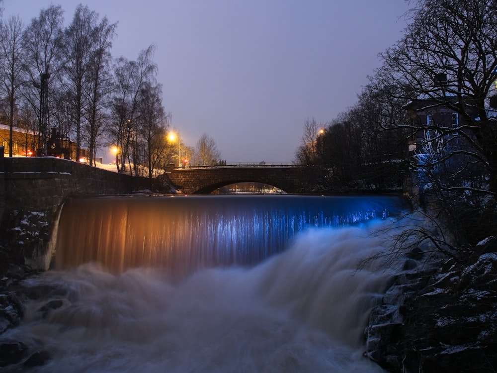 a waterfall with a bridge in the background