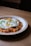 A plate of kimchi fried rice topped with a sunny-side-up egg, garnished with chopped green onions, is placed on a wooden table.