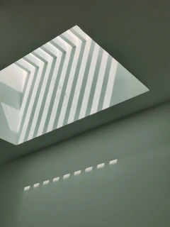 Abstract composition of shadows and light creating geometric shapes on a plain wall.