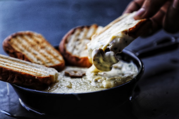 Close-up of a steaming fondue pot surrounded by fresh bread and smiling diners.