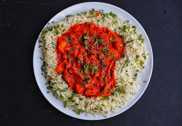 Artfully plated Kerala-style curry and rice with fresh herbs, captured in warm earthy tones.